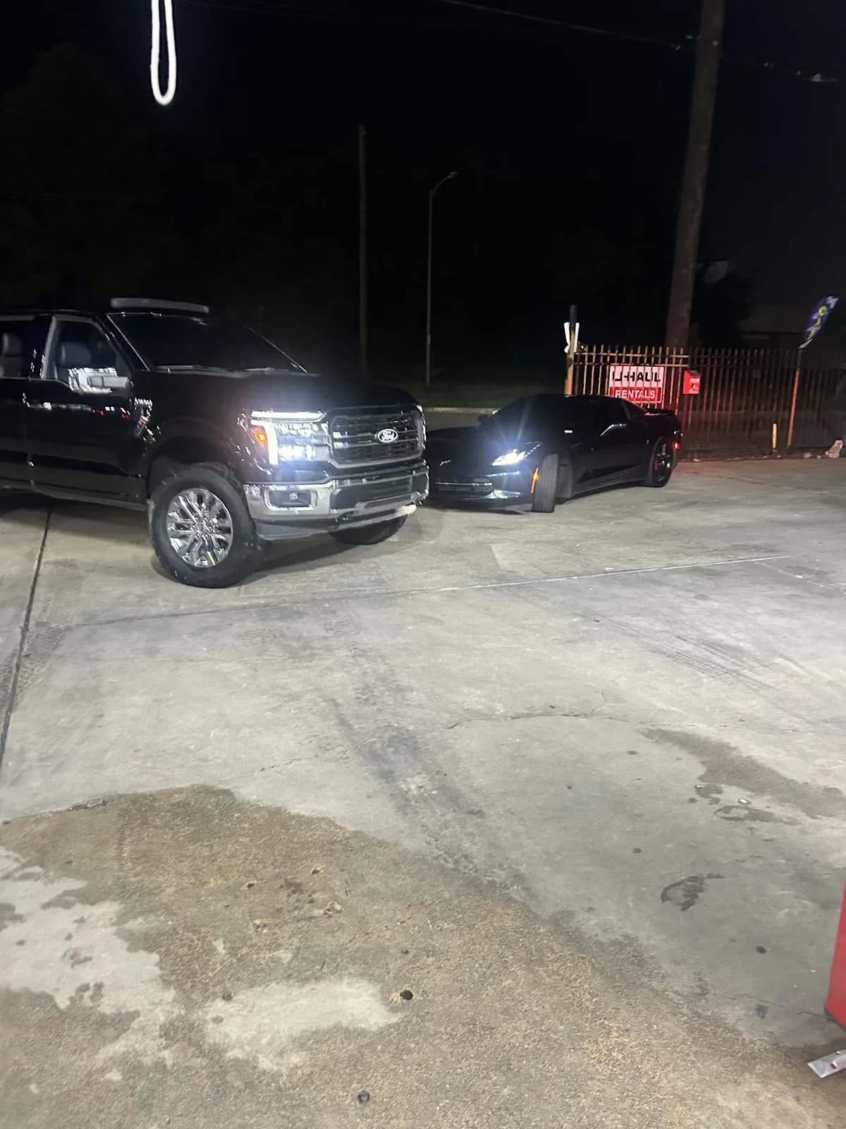 Black Ford truck and sports car detailed under the night lights